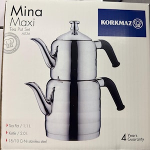 May include: A stainless steel Mina Maxi tea pot set. The set includes a 1.1 liter tea pot and a 2.0 liter kettle. The set is made of 18/10 Cr-Ni stainless steel. The box also features the Korkmaz logo and a 4-year guarantee.