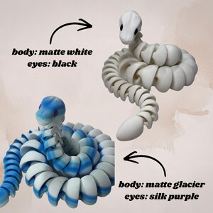 May include: Two articulated snake toys. One is matte white with black eyes, and the other is matte glacier with silk purple eyes. The text on the image reads "body: matte white eyes: black" and "body: matte glacier eyes: silk purple."
