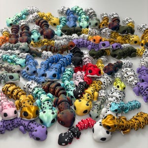 May include: A collection of colorful, articulated caterpillar toys in various colors, including blue, yellow, red, and purple. Each caterpillar has a spotted pattern and a smiling face. The toys are made of plastic and are designed to be flexible.