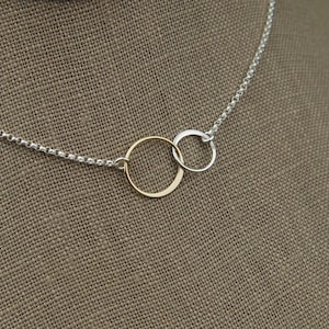 May include: A silver chain necklace with two interlocking circles, one gold and one silver.