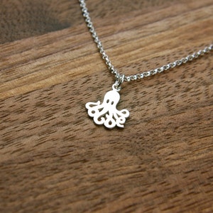 Puede incluir: Un collar de plata con un delicado colgante de pulpo. El pulpo est&aacute; cortado en el metal y tiene un dise&ntilde;o detallado.
