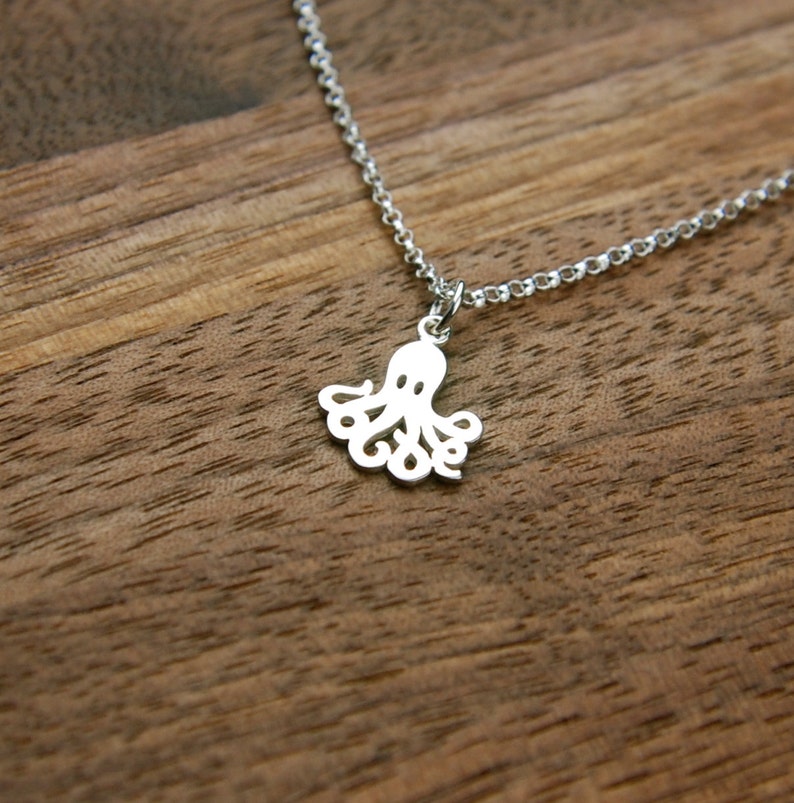 Puede incluir: Un collar de plata con un delicado colgante de pulpo. El pulpo est&aacute; cortado en el metal y tiene un dise&ntilde;o detallado.