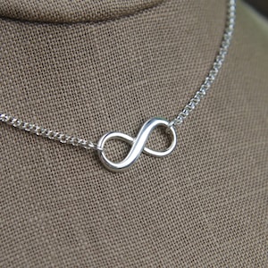 May include: A silver infinity symbol necklace with a delicate chain.