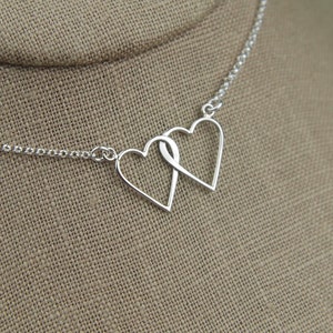 May include: A silver necklace with a double heart pendant. The hearts are intertwined and form a delicate design.