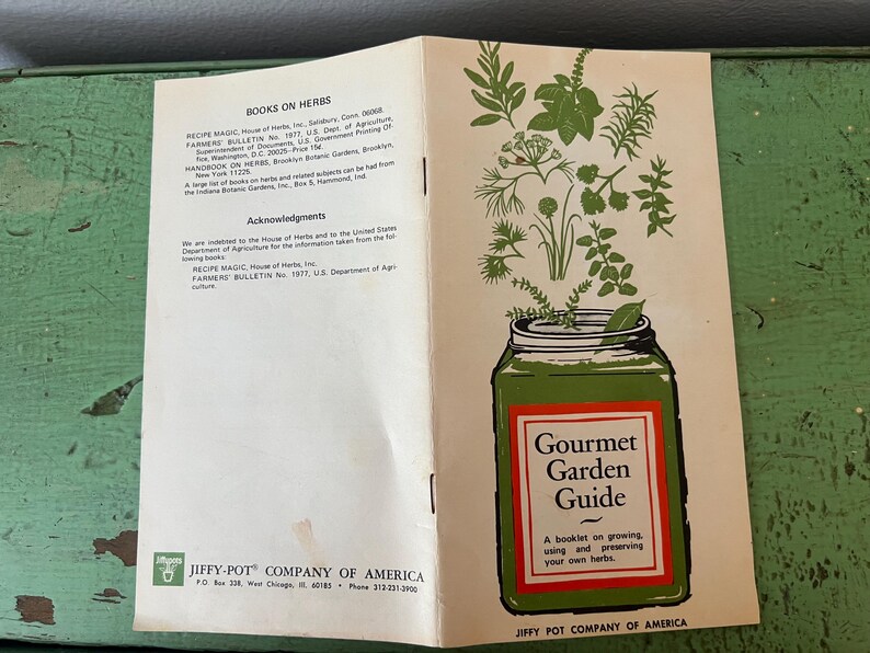 May include: Open vintage booklet titled "Gourmet Garden Guide" with a green jar illustration and herbs. The booklet is open, showing text about herbs and acknowledgments. The cover features the text "Gourmet Garden Guide".
