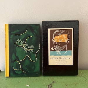 May include: Two vintage books. The first book has a dark green cover with a silhouette and gold detailing. The second book is in a black box with a portrait and the title "Green Mansions".