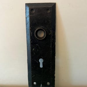 Puede incluir: Una taza de cerámica blanca con un asa negra y el texto "But First, Coffee" en negro, con una fuente de estilo manuscrito. La taza está sobre una superficie blanca.