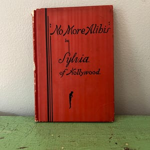 May include: A vintage book titled "No More Alibis" by Sylvia of Hollywood. The book has a red cover with black text and a stylized silhouette. The book is slightly worn, suggesting its age.