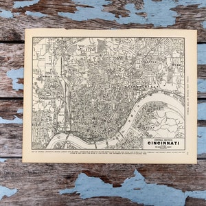 Puede incluir: Un mapa antiguo en blanco y negro de Cincinnati, Ohio. El mapa, titulado "Central Section Cincinnati", muestra el diseño de la ciudad, incluyendo calles, edificios y el río Ohio. Impreso en papel envejecido.