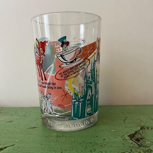 May include: Clear glass featuring Disney characters and text. The design includes Bambi, a teacup, and a castle, with text stating "You would need 329 gallons of tea to fill up a tea cup found in Fantasyland."