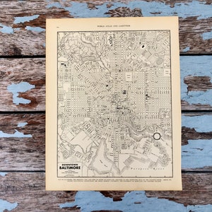 May include: A vintage map of downtown Baltimore, from the World Atlas and Gazetteer. The map is in black and white, showing detailed street layouts and the Patapsco River. The title "Downtown Baltimore" is visible. The map is on aged paper.