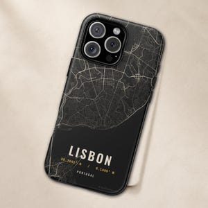 May include: A black smartphone case featuring a detailed white street map of Lisbon, Portugal. The design includes the text LISBON, the coordinates 38.7241 N / 9.1486 W, and the word PORTUGAL in a clean, sans-serif font at the bottom of the case.
