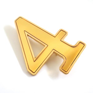 May include: A gold-colored metal number four pin. The pin is in the shape of the number four with a rectangular base. The pin has a shiny, reflective surface and is set against a white background.