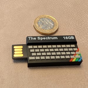 May include: A black USB flash drive shaped like a vintage computer with a keyboard and rainbow coloured accents. The drive is labelled "The Spectrum 16GB".