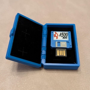 May include: A blue plastic case with a black interior, open to reveal a small blue and white USB flash drive with the text "A500 MINI 32" printed on it.