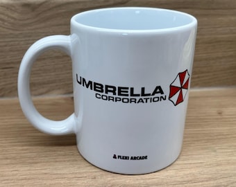 May include: A white ceramic mug featuring the black text Umbrella Corporation and a red and white umbrella logo on the side. Near the base, the text Flexi Arcade is printed in black with a small red icon of a person next to the brand name.