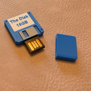May include: A blue and white 16GB USB flash drive shaped like a floppy disk. The drive has a blue plastic case and a silver metal slider. The drive is labeled "The Disk 16GB".