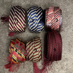 May include: Six spools of red, blue, and gold striped trim with tassels. The spools are numbered 1 through 6.
