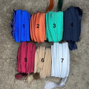 May include: Seven different colors of ribbon with tassels. The colors are blue, orange, green, navy, burgundy, beige, and white.