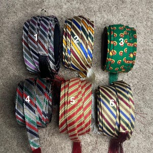 May include: Six rolls of striped fabric ribbon with different color combinations. The ribbon is rolled up and tied with a string. The ribbon is numbered 1 through 6.