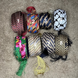 May include: Eight different patterned ribbon trims with tassels. The trims are in various colors, including red, blue, green, black, white, and gold. Each trim is numbered 1 through 8.