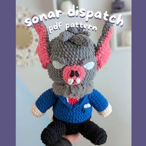 Puede incluir: Muñeca de murciélago de ganchillo hecha a mano con el texto "sonar dispatch pdf pattern". El murciélago tiene pelaje gris, orejas rosas, hocico rosa y ojos blancos. Lleva una chaqueta azul, una corbata roja y pantalones negros.