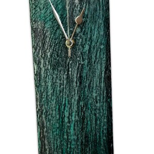 May include: A green and black slate clock with silver hands.