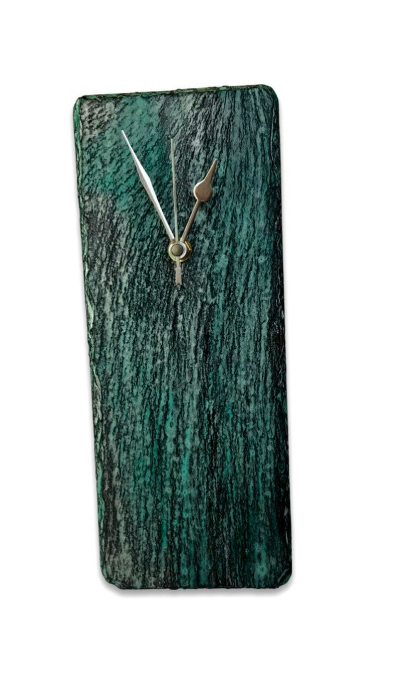 May include: A green and black slate clock with silver hands.