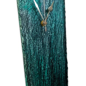 May include: A teal green slate clock with silver hands and a gold center. The clock has a rough, textured surface.