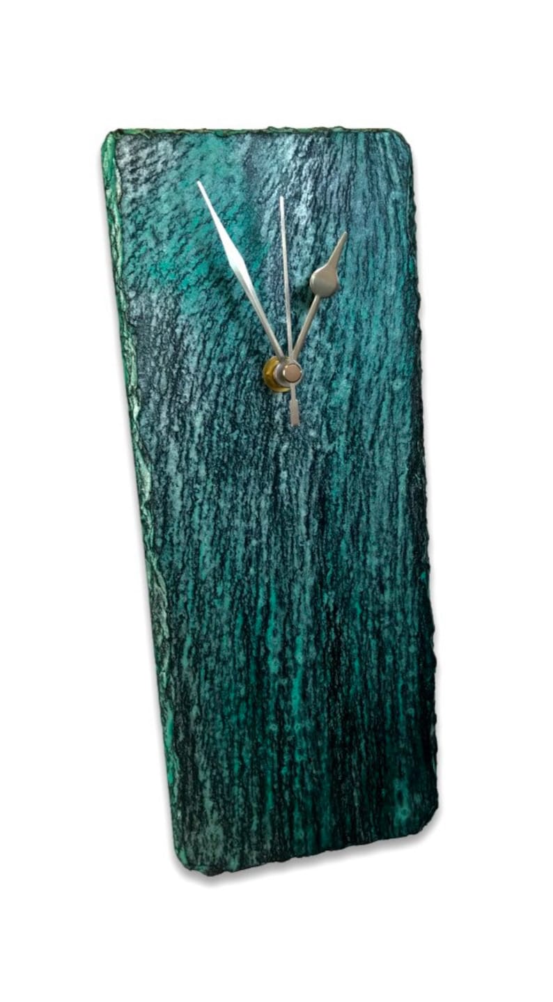 May include: A teal green slate clock with silver hands and a gold center. The clock has a rough, textured surface.