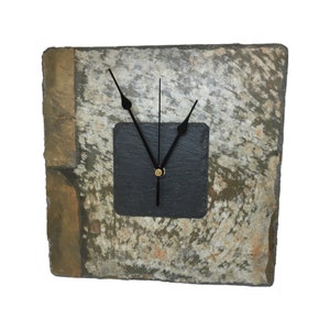 May include: Square slate clock with a black square clock face. The clock face has black hands and a gold-colored center. The slate has a natural, textured appearance with shades of gray, brown, and tan.