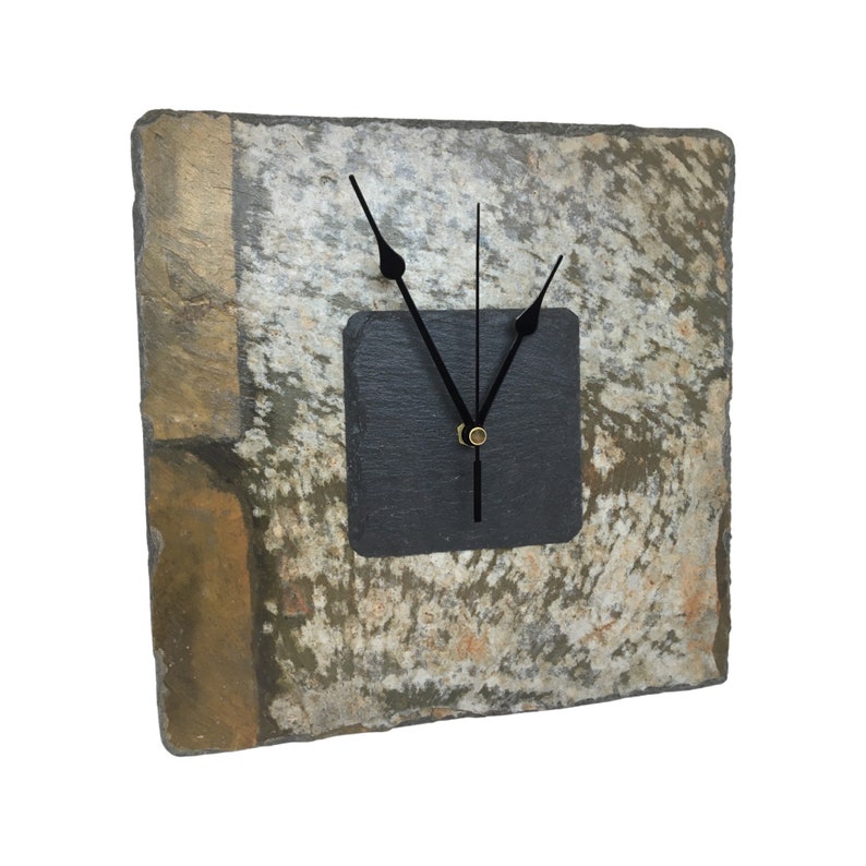 May include: Square slate clock with black clock hands and a black square clock face. The clock face is set into a larger square of natural stone with shades of gray, brown, and gold. The clock hands are black.