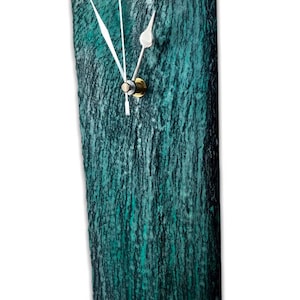 May include: A teal green rectangular wall clock with white hands and a gold knob. The clock face has a textured, wood-like surface.