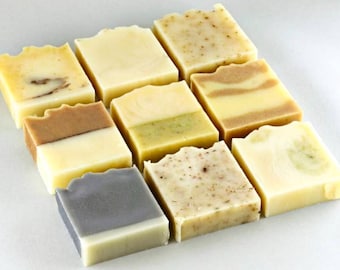 May include: Nine bars of handmade soap in various colors and patterns. The soaps are arranged in a grid pattern on a white surface.