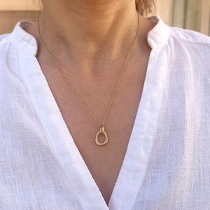 May include: A gold chain necklace with a simple, oval-shaped pendant.
