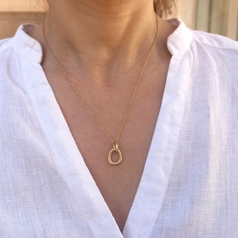May include: A gold chain necklace with a simple, oval-shaped pendant.