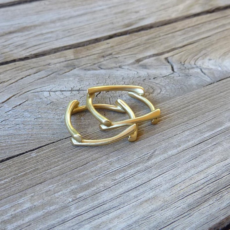 May include: Two gold-colored metal rings, stacked on top of each other, on a wooden surface.
