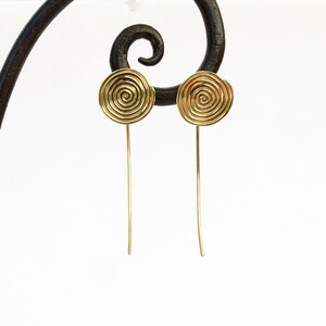 May include: A pair of gold earrings with a spiral design. The earrings are long and thin, with a small round disc at the top.