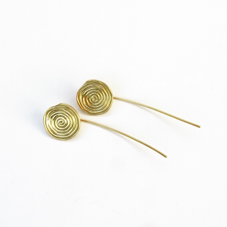 May include: A pair of gold earrings with a spiral design. The earrings are long and thin, with a small, round spiral at the end.