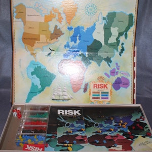 May include: A vintage Risk board game with a world map, game pieces, and cards. The game is in its original box, which is open and shows the contents of the game.