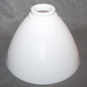 May include: White glass lampshade with a textured, ribbed pattern. The shade is cone-shaped and has a smooth, white rim.