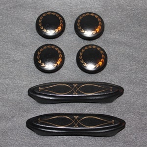 May include: Four black round knobs with gold leaf accents and two black drawer pulls with gold leaf accents.