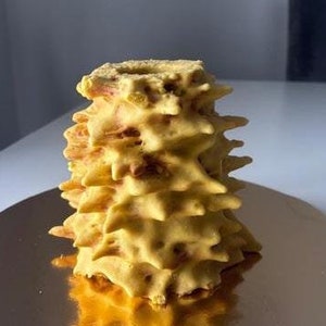 Könnte beinhalten: Ein gelber, mehrschichtiger Kuchen mit sternförmigem Design, der auf einem goldfarbenen Teller liegt.