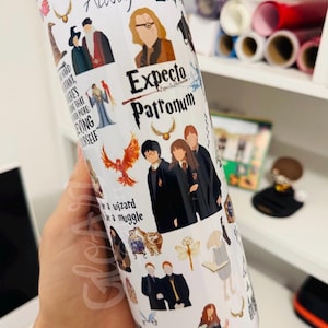 May include: A white cylindrical tumbler featuring a collage of colorful illustrations of characters and magical items from a fantasy series, including text that reads "After all this time? Always," "Expecto Patronum," and "be a wizard be a muggle."