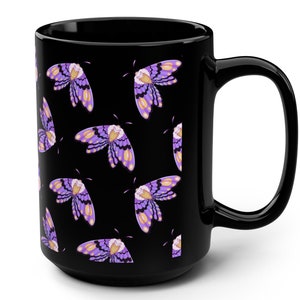 Può includere: Tazza da caffè nera con un motivo a farfalla viola e gialla.