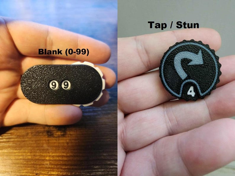 Pu&ograve; includere: Due contatori di gioco in bianco e nero. Il contatore a sinistra ha una forma ovale allungata con il testo Blank (0-99) e il numero 99. Il contatore a destra &egrave; circolare con un bordo seghettato, il testo Tap / Stun e il numero 4.