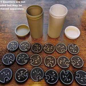 Peut inclure: Vue aérienne d'accessoires de jeu. Deux contenants cylindriques, vert olive et blanc, sont ouverts. En dessous, des compteurs noirs et blancs avec "+1/+1" et des chiffres. Le texte "+1/+1 Counters are not included but may be purchased separately" est visible. Accessoires pour jeu de société.