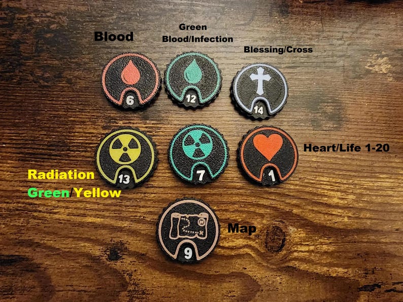 Pu&ograve; includere: Sette gettoni da gioco circolari neri con bordi testurizzati. Ogni gettone presenta un'icona unica: una goccia di sangue rossa, una goccia di sangue verde, una croce bianca, un simbolo di radiazione giallo, un simbolo di radiazione verde, un cuore arancione e una mappa bianca.