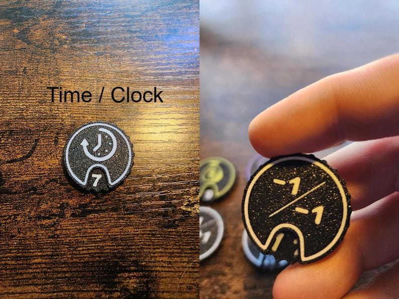 Pu&ograve; includere: Un gettone nero circolare con bordo bianco e un'icona bianca di un orologio con una freccia in senso antiorario sopra il numero 7, etichettato Time / Clock. Un altro gettone nero presenta una linea diagonale bianca che separa due valori -1.