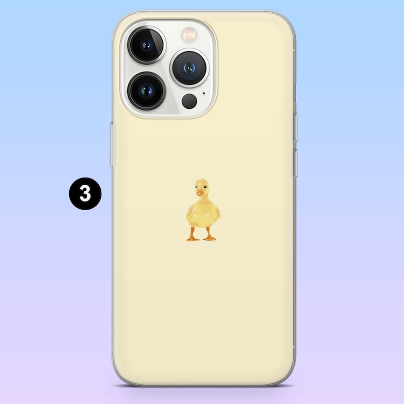 May include: A light yellow phone case with a watercolour illustration of a yellow duckling. The phone case has a clear border and a light yellow background. The number "3" is in a black circle in the upper left corner.
